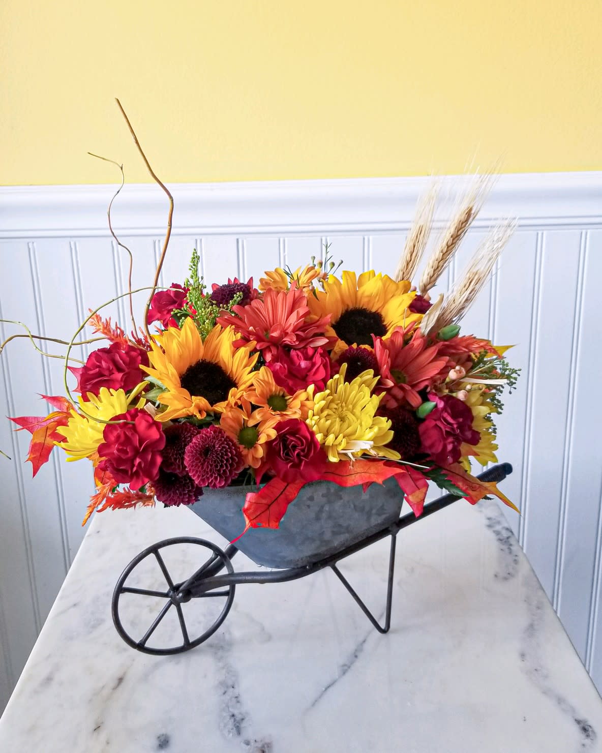 Colorful fall flower arrangement in a wheelbarrow-shaped container