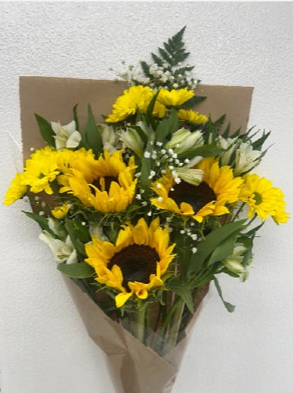 Bouquet of yellow sunflowers and white lilies wrapped in brown paper