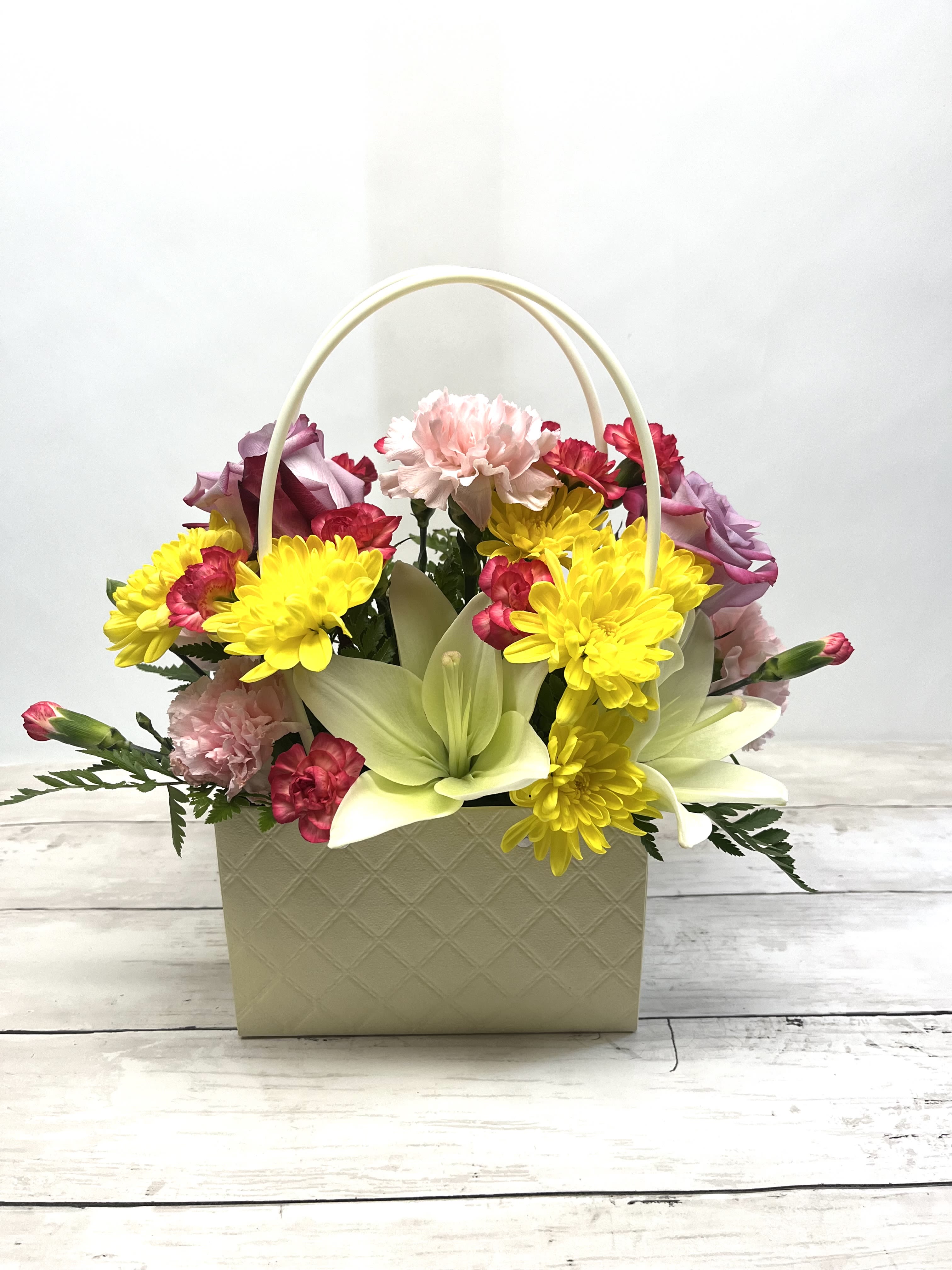 Basket arrangement with yellow daisies, pink carnations, and pale lilies