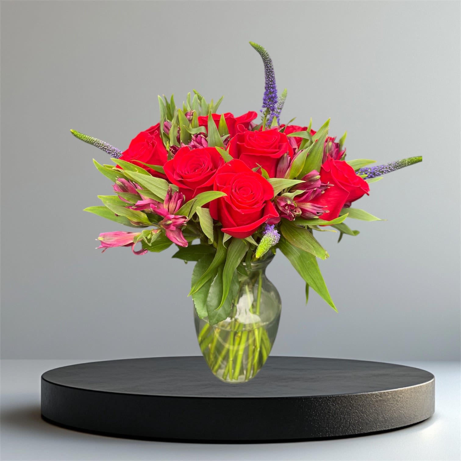 Red roses and pink flowers in a clear glass vase