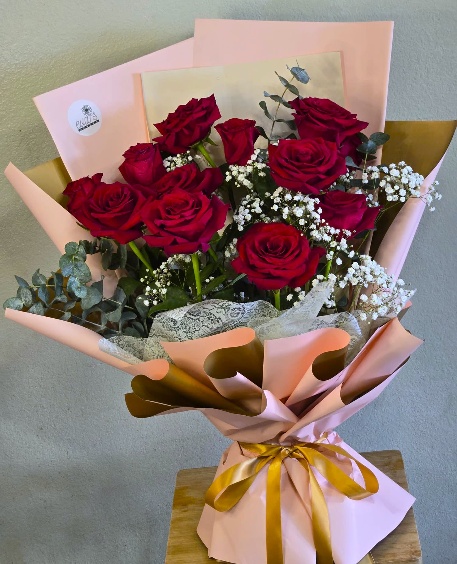 Bouquet of red roses with baby's breath in pink and gold wrapping