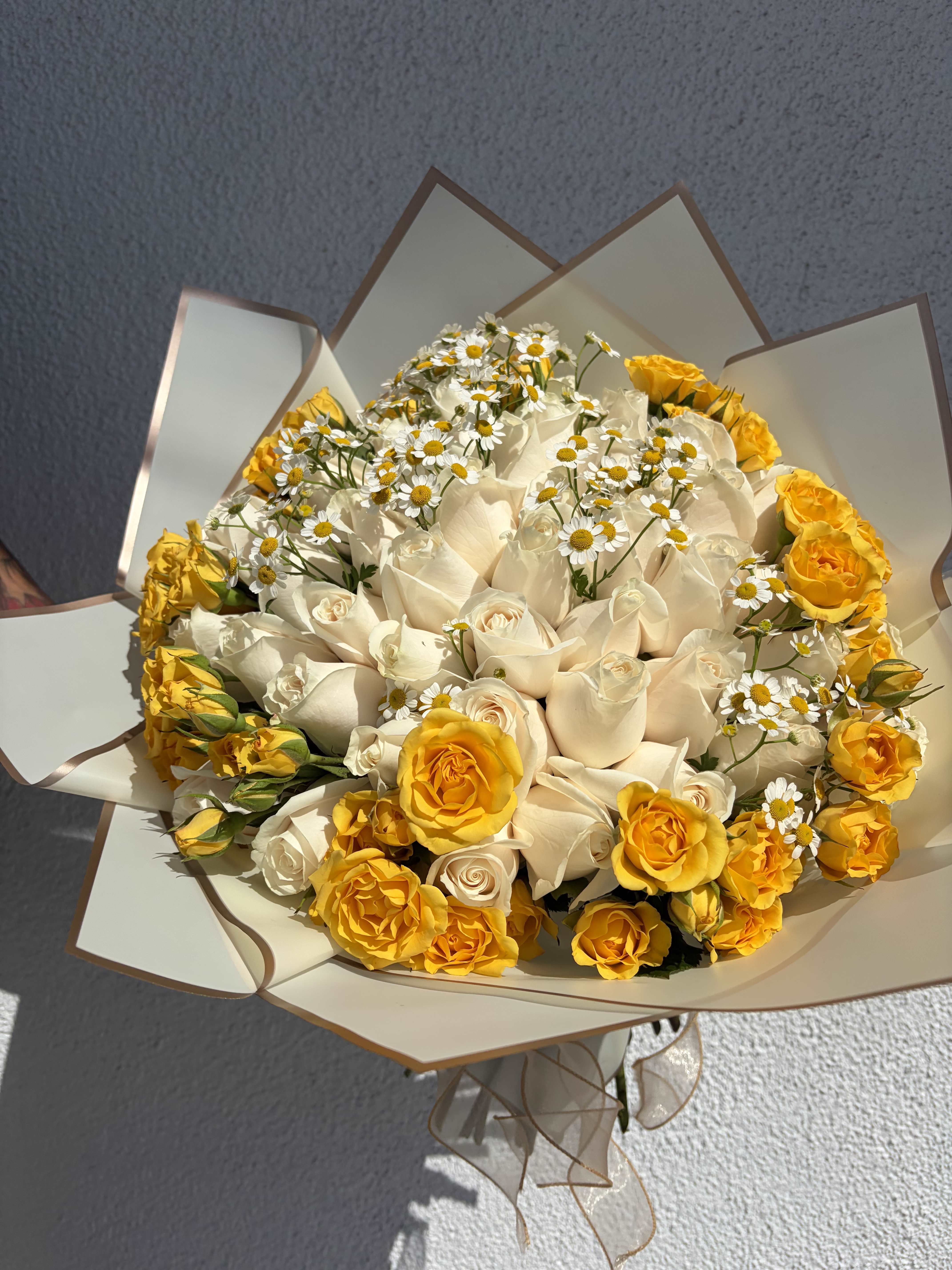 Bouquet of white and yellow roses with small white daisies