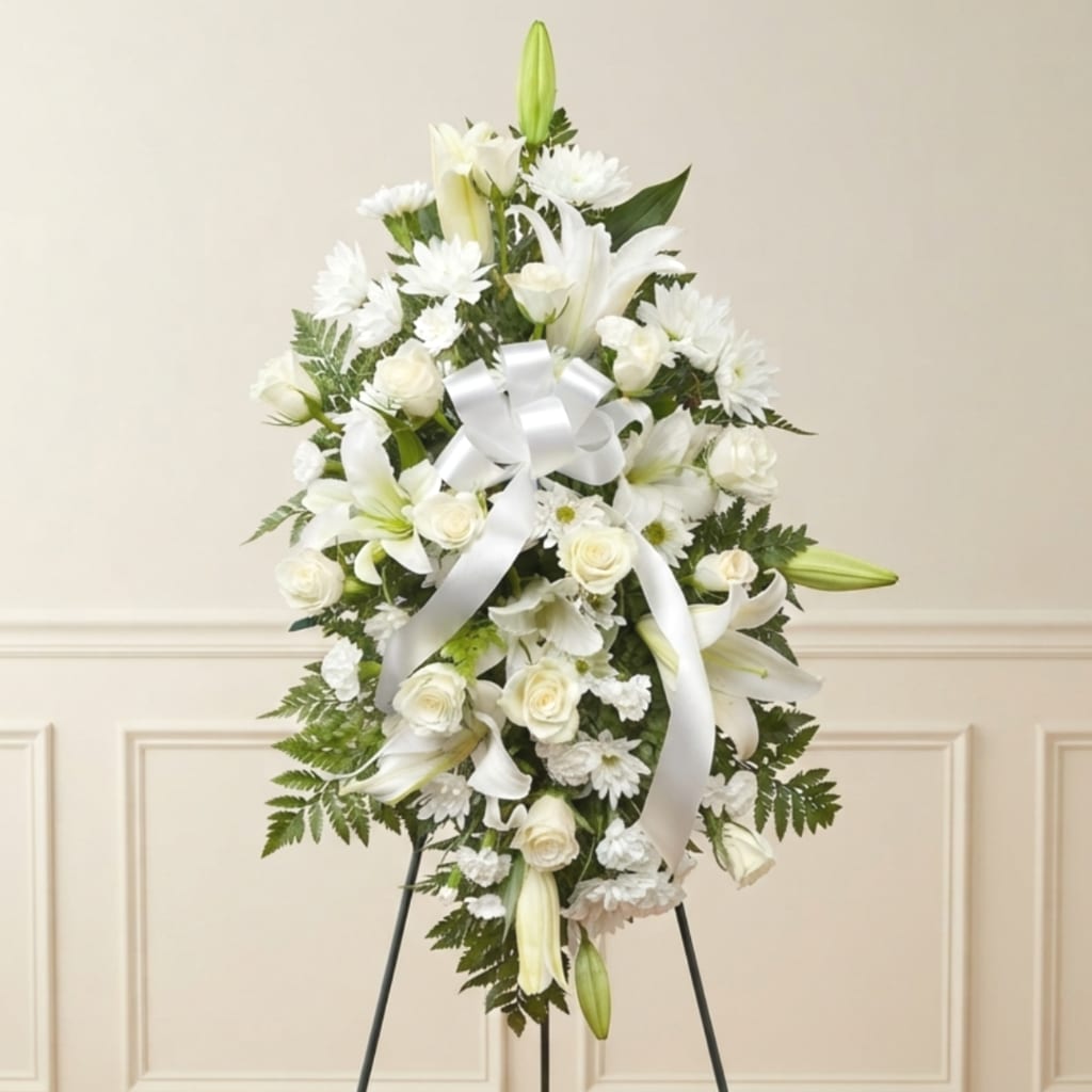White floral standing spray with lilies, roses, and daisies on an easel