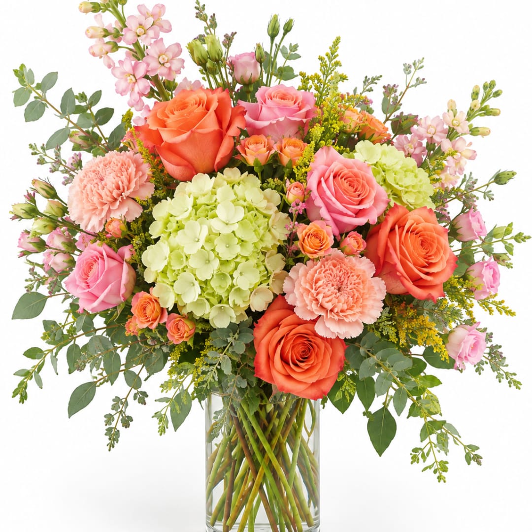 Mixed bouquet of roses, hydrangea, and carnations in a clear glass vase