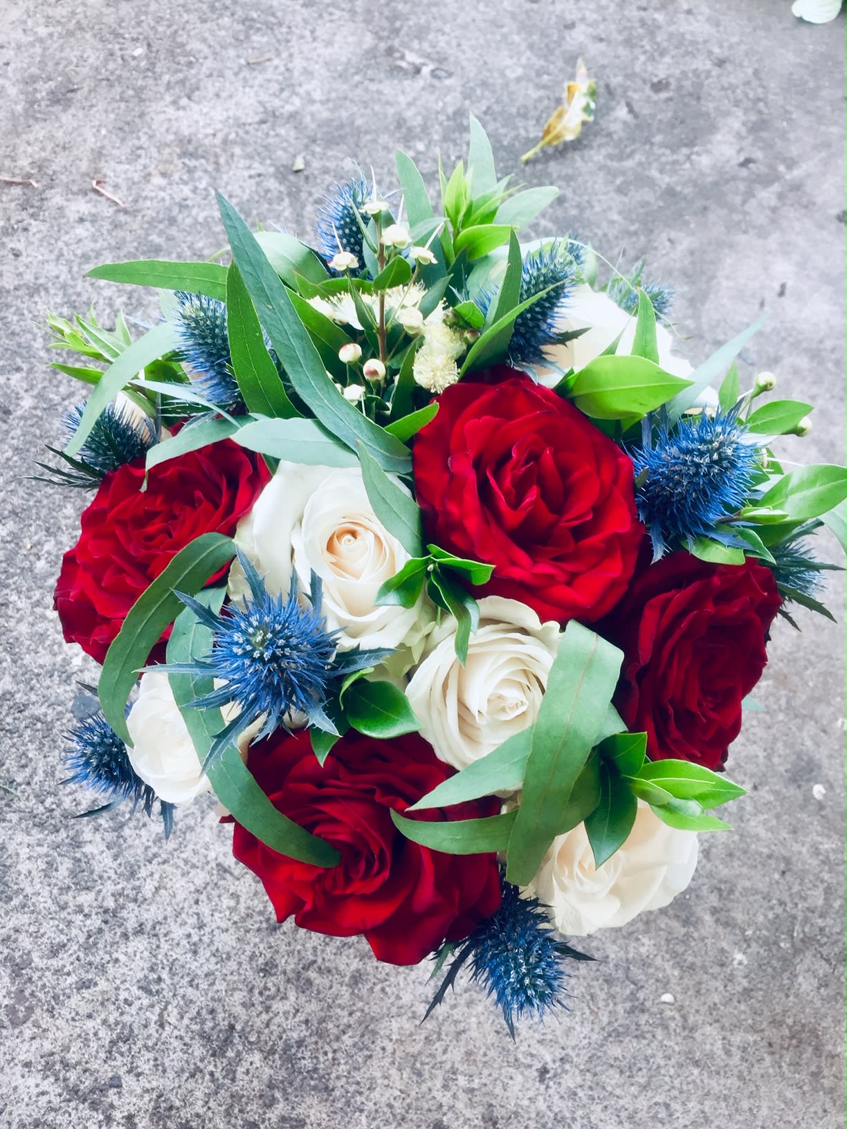 Bouquet of red and white roses with blue thistle accents