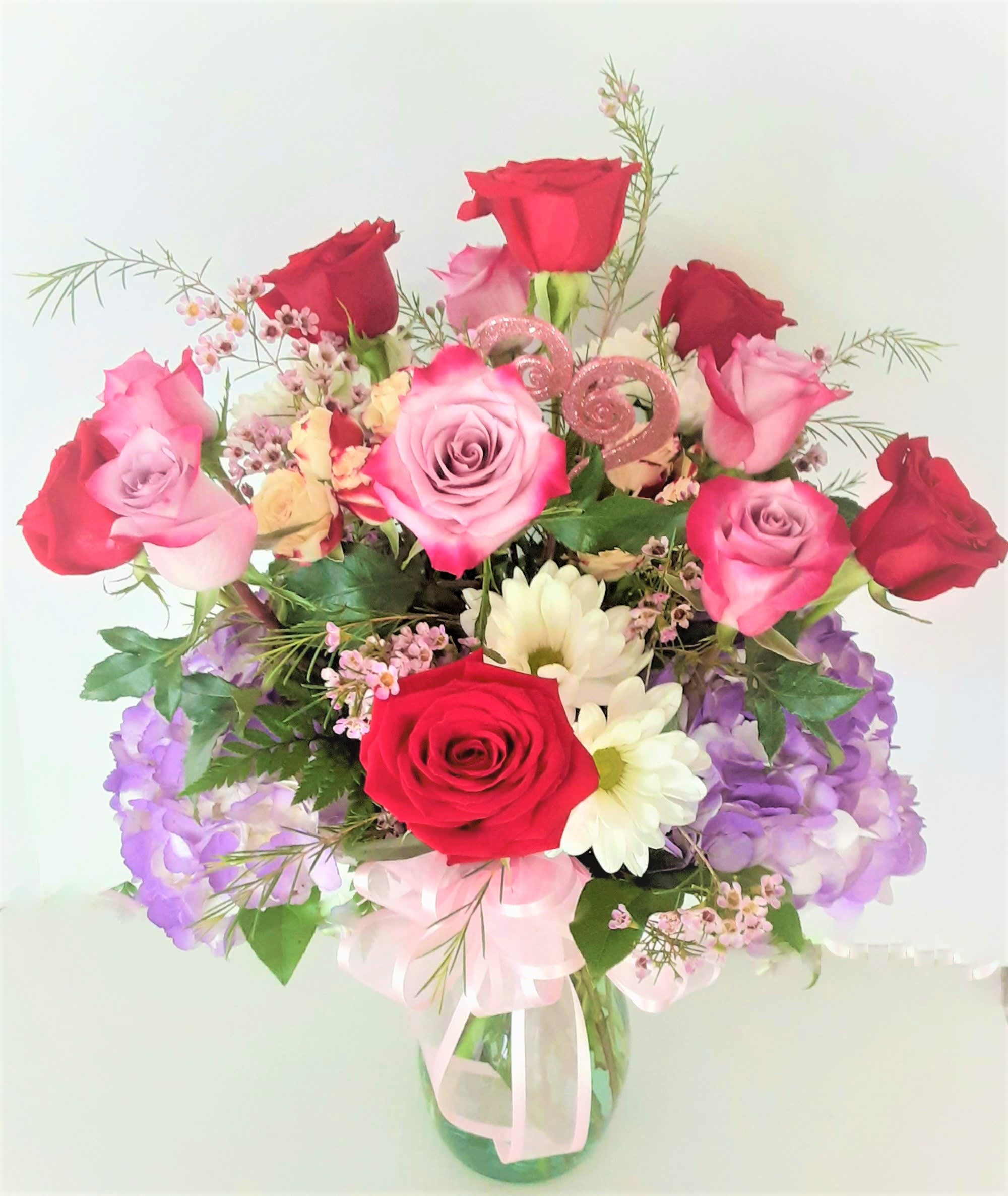 Bouquet of red and pink roses with purple flowers in a glass vase