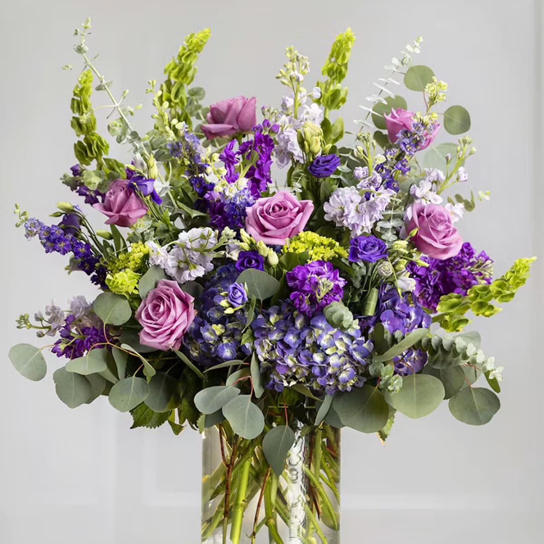 Tall bouquet of purple and pink flowers in a clear glass vase