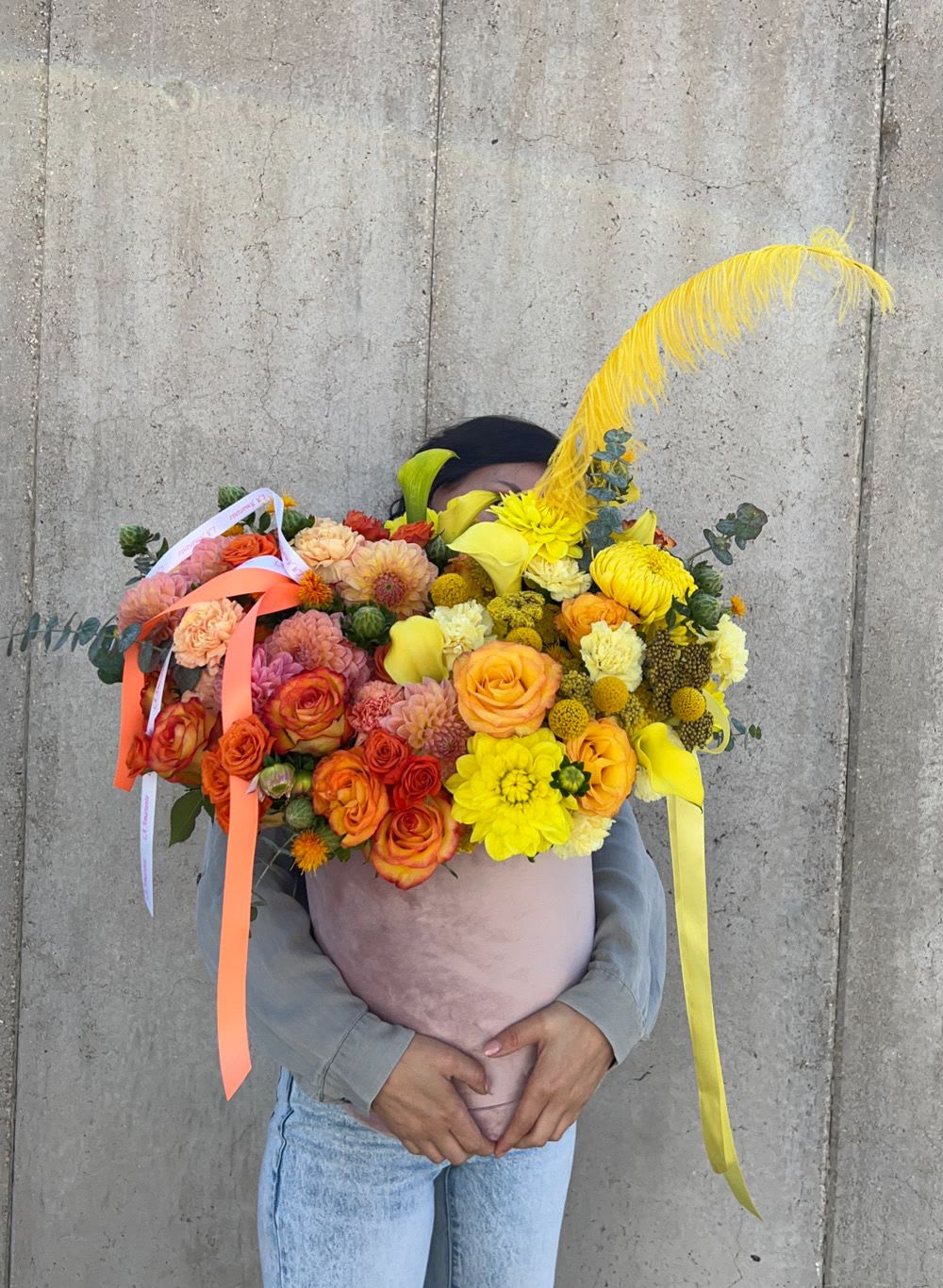 Large bouquet of orange, yellow, and pink flowers with ribbons