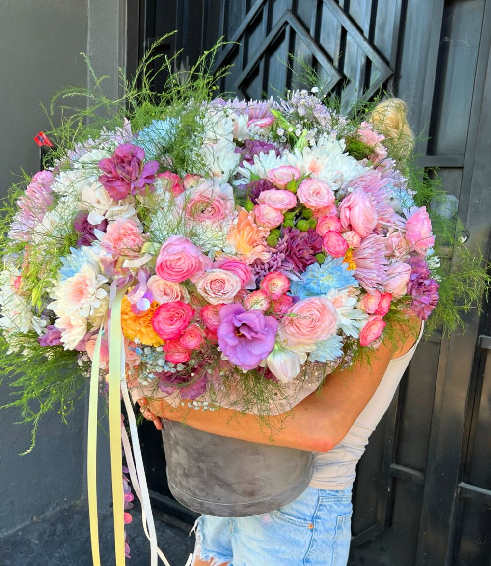 Large pastel bouquet in a gray bucket with pink, white, and purple flowers
