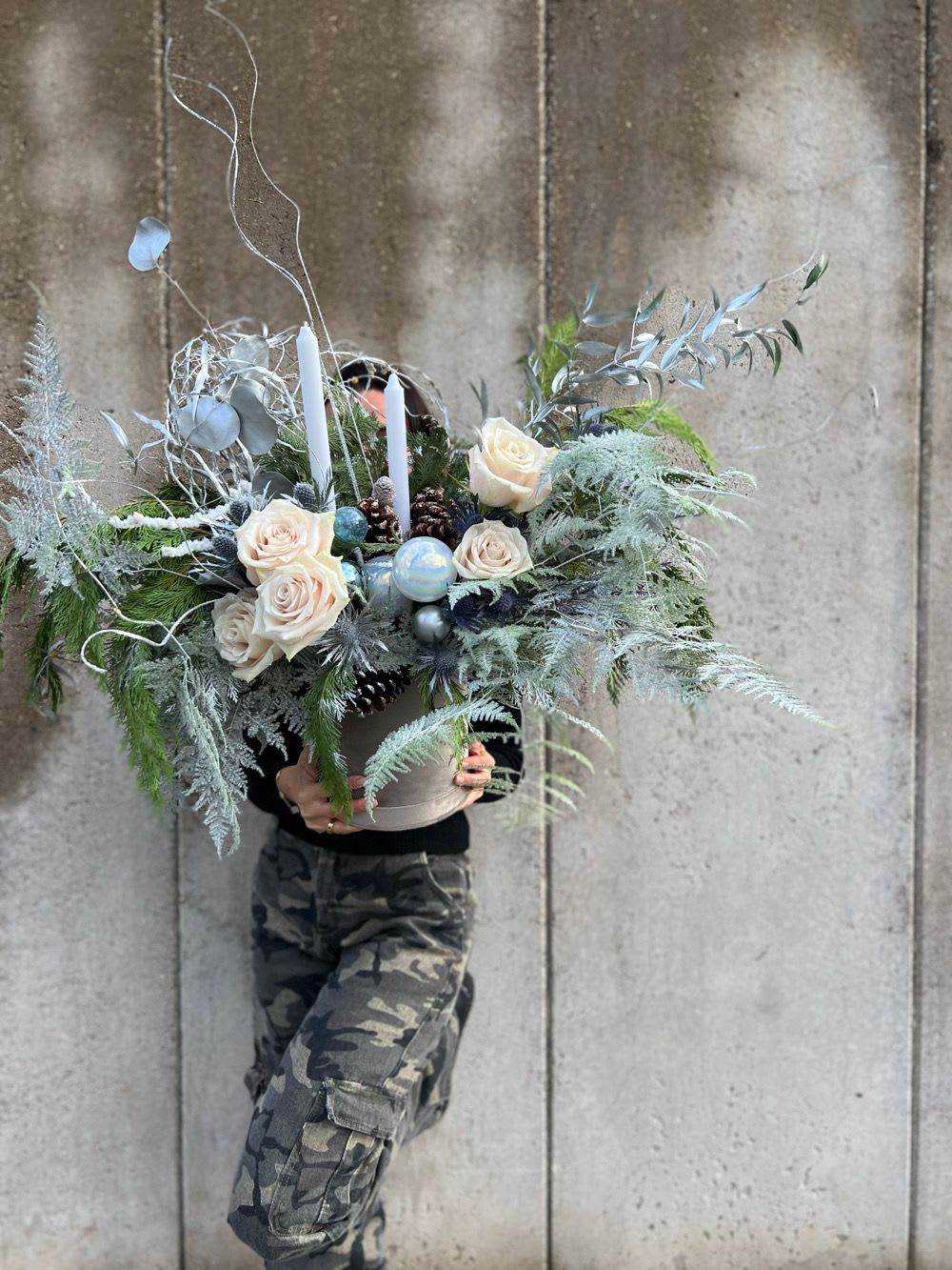 Large winter floral arrangement with white roses and candles in a container