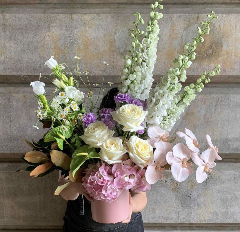Mixed bouquet in a pink hatbox with white, pink, and purple flowers