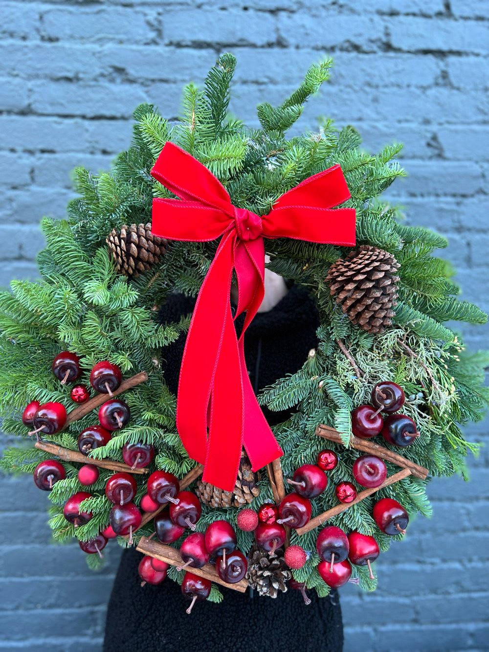 Evergreen wreath with red ribbon, pinecones, and red berry accents