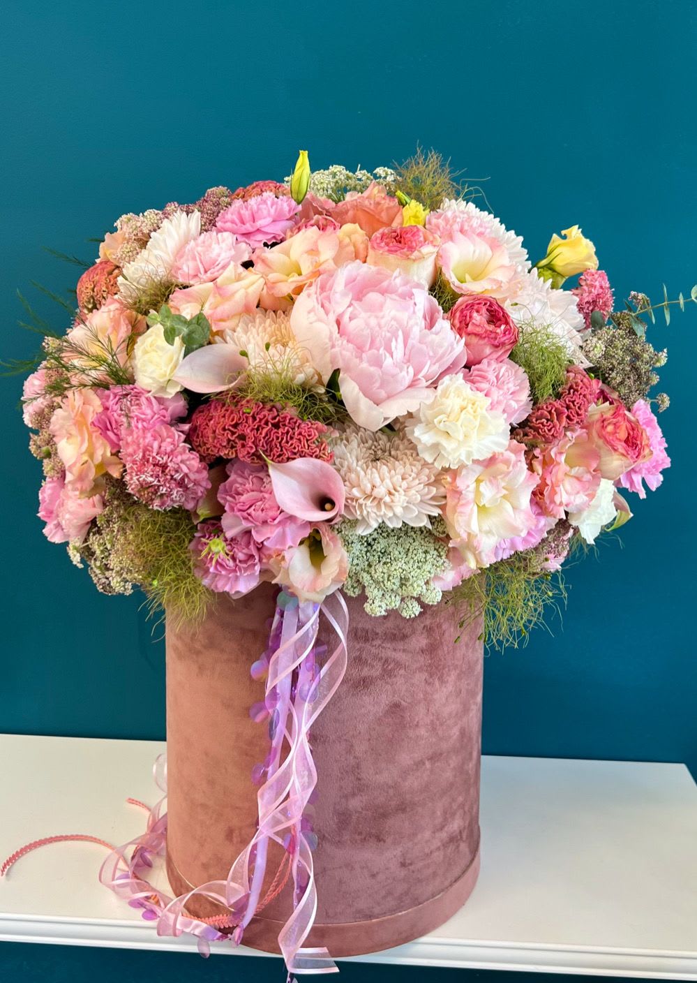 Large pink and peach mixed flower arrangement in a velvet hat box