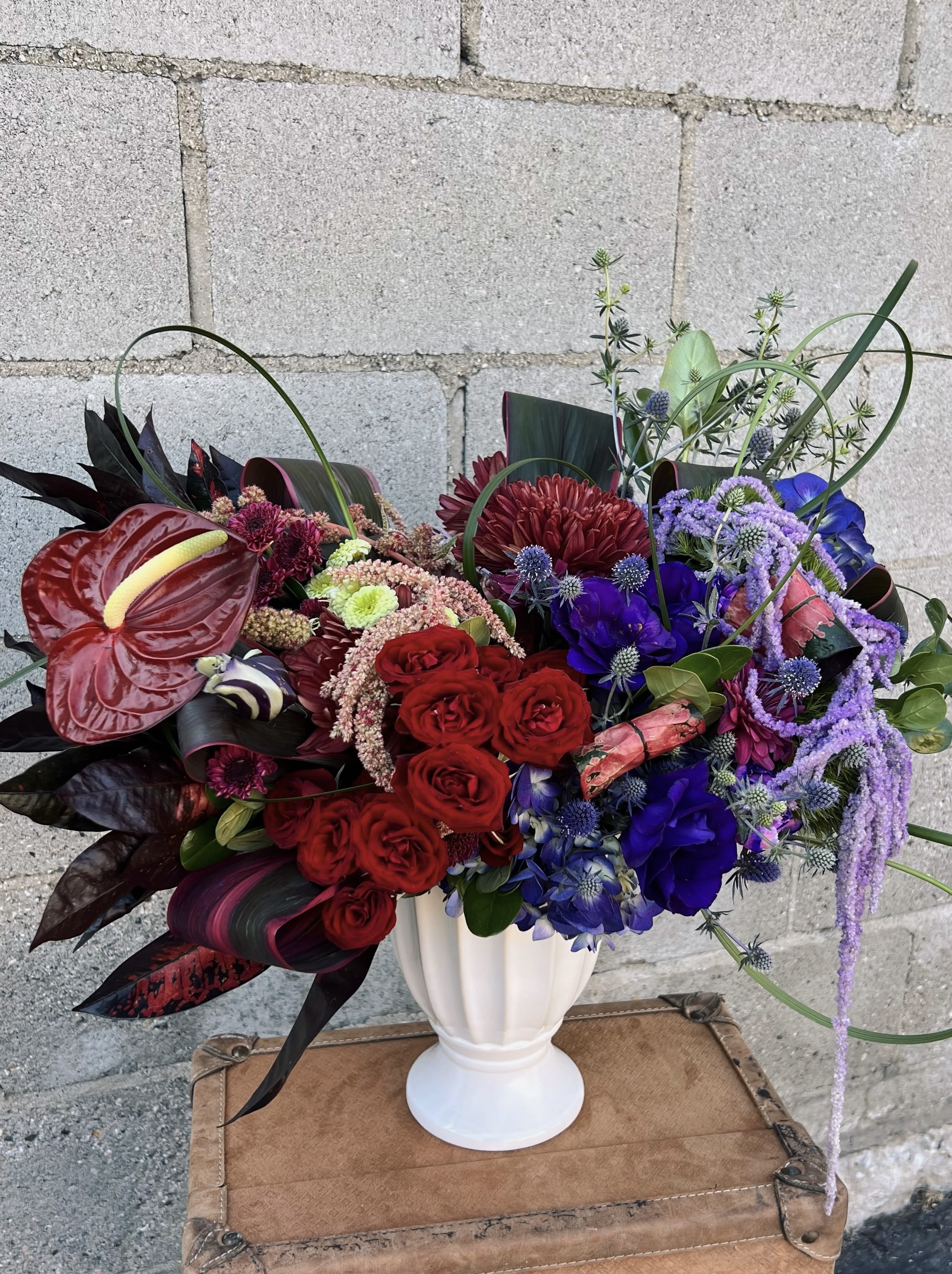 Bold mixed bouquet in a white vase with red, purple, and blue flowers
