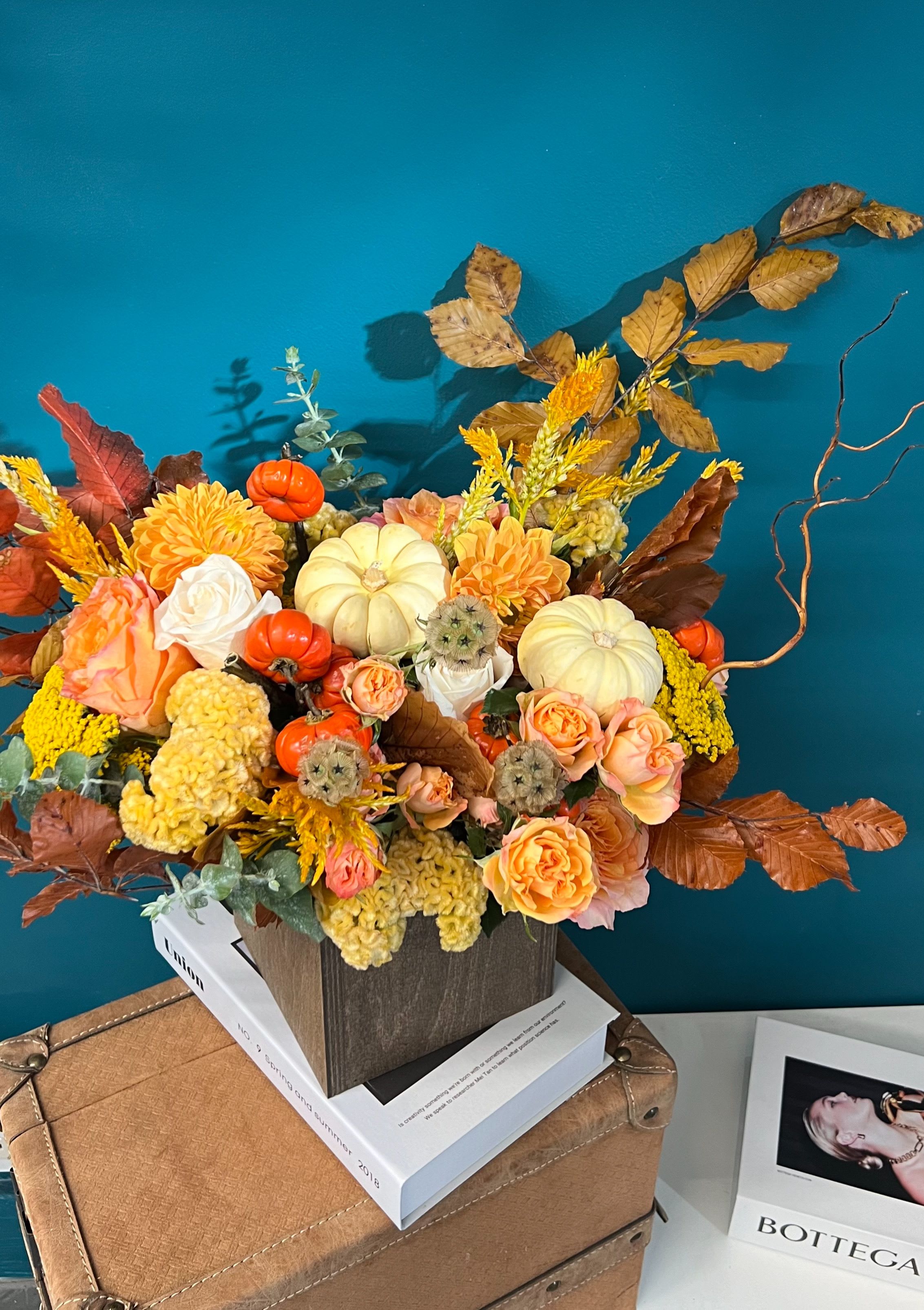 Autumn floral arrangement with pumpkins and orange roses in a square container