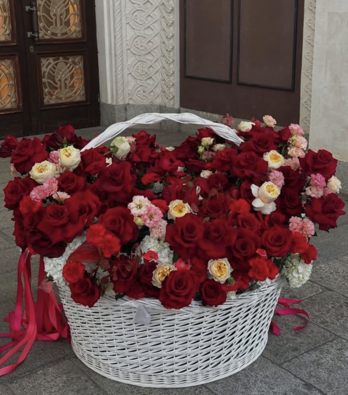 Large white basket filled with red and pink roses