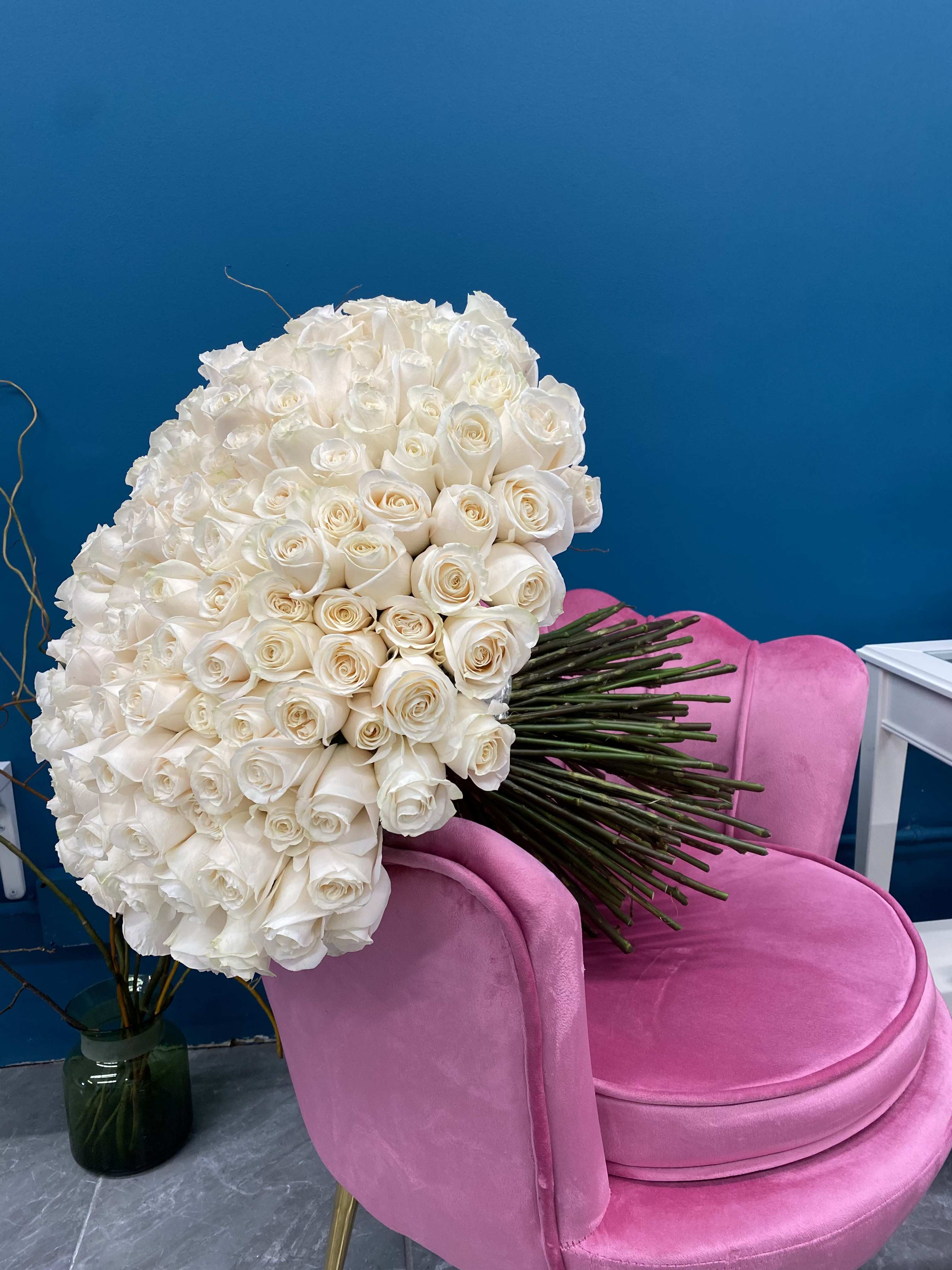 Large bouquet of white roses resting on a pink chair