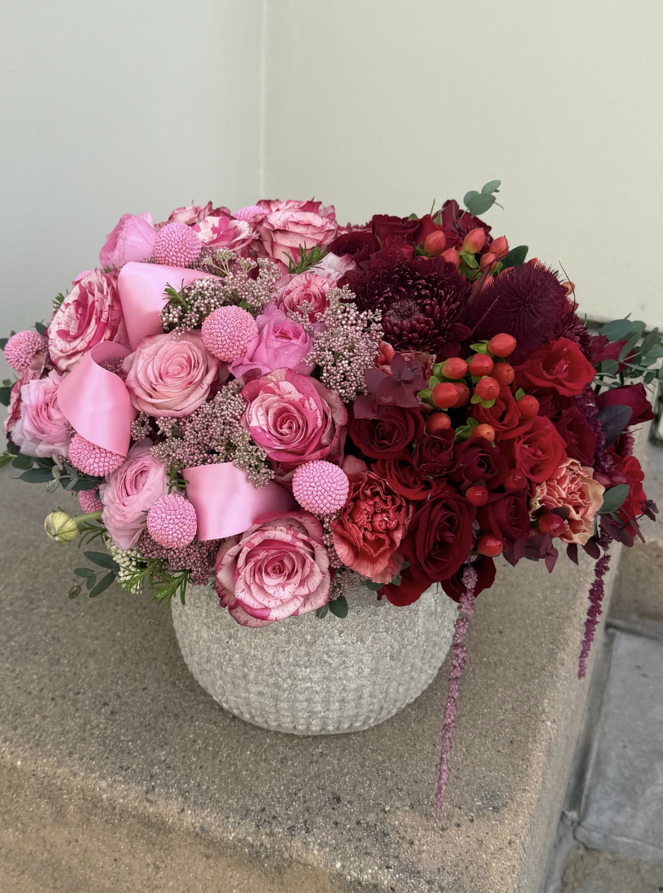 Pink and red rose arrangement in a textured stone vase
