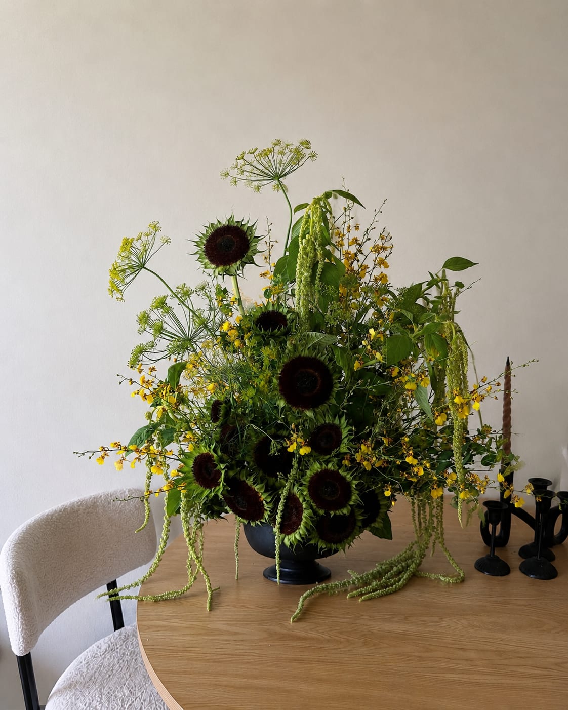 Large floral arrangement with dark sunflowers and yellow blooms in a black vase