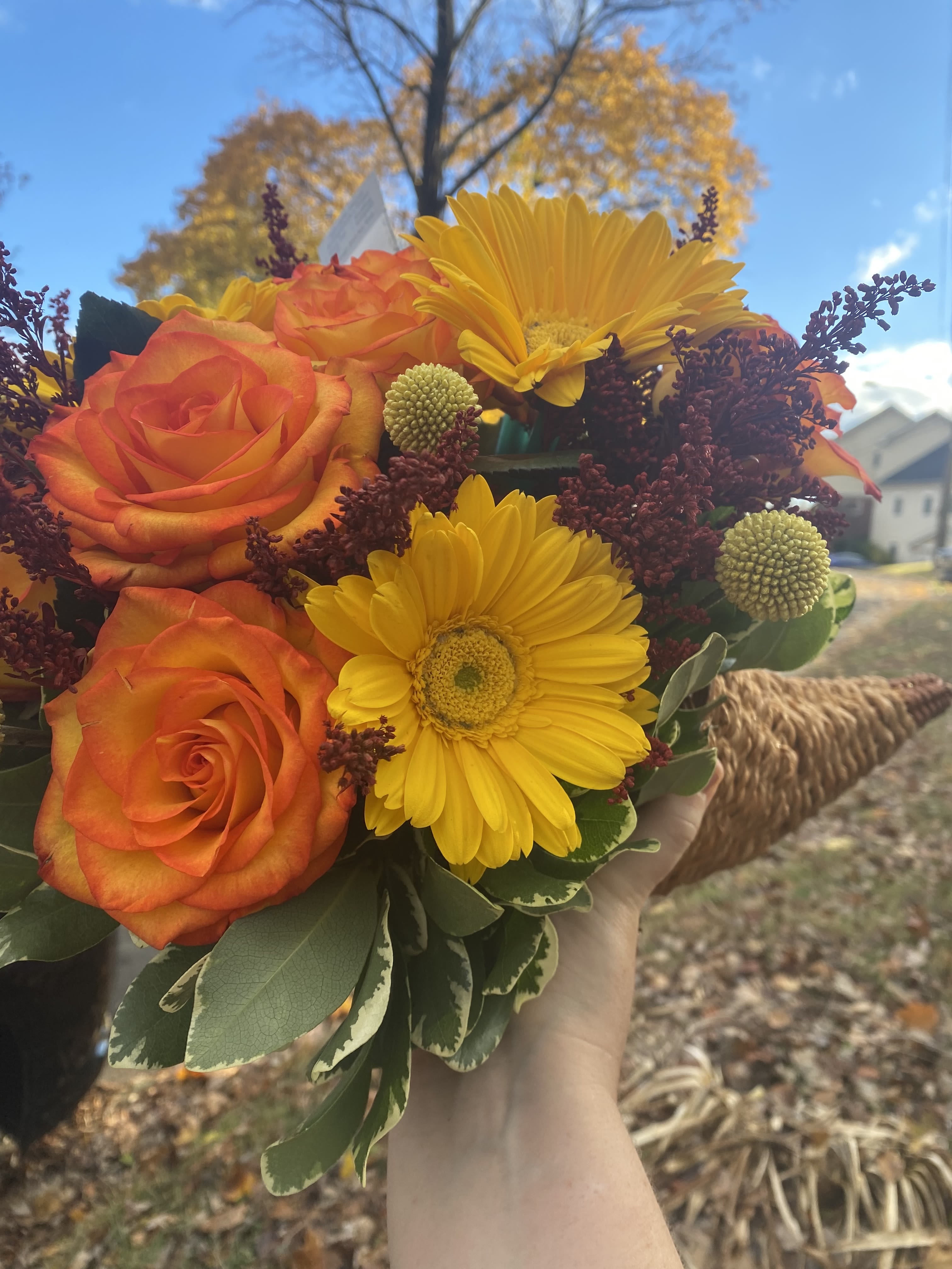 Handheld bouquet of orange roses and yellow gerbera daisies