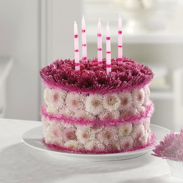 Round floral cake with pink candles on a white plate