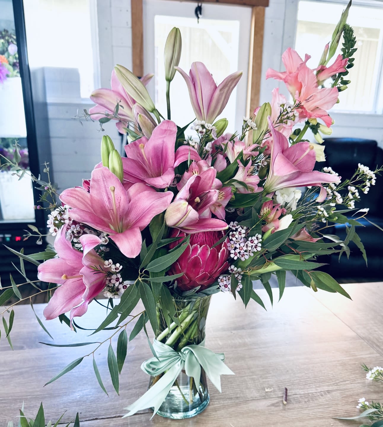 Protea? Protea sí - Protea Sí is a bold, modern arrangement centered around the striking beauty of premium protea.   Designed with a curated mix of complementary blooms and textured greenery, this piece highlights natural form, depth, and movement.   Each arrangement is created at the designer’s discretion, resulting in a unique composition with a refined, contemporary feel.   Perfect for making a statement or adding a distinctive touch to any space.   Flower varieties and tones may vary based on availability. Each arrangement is uniquely designed while maintaining the overall style and aesthetic.