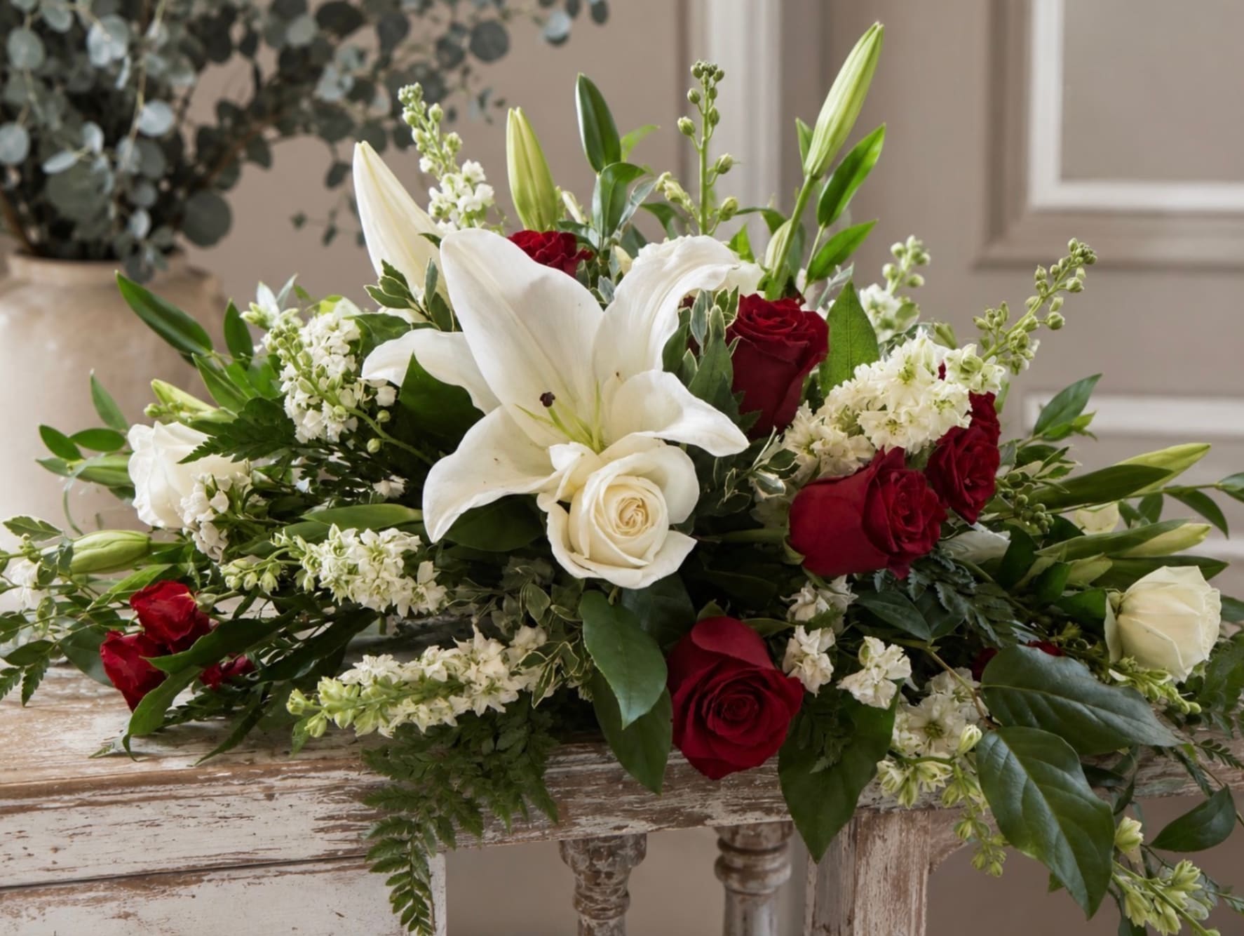 White lilies and red roses arranged in a low centerpiece