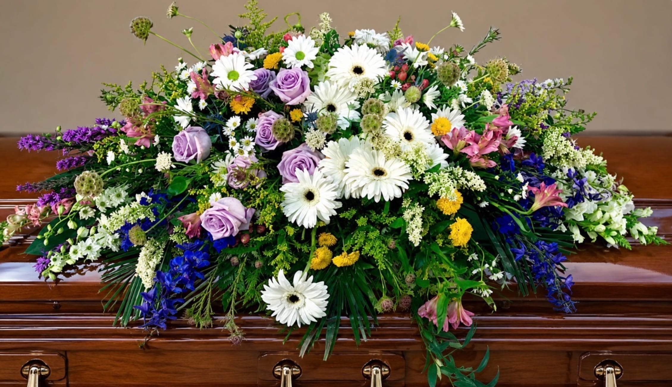 Large casket spray with white daisies, lavender roses, and mixed blooms