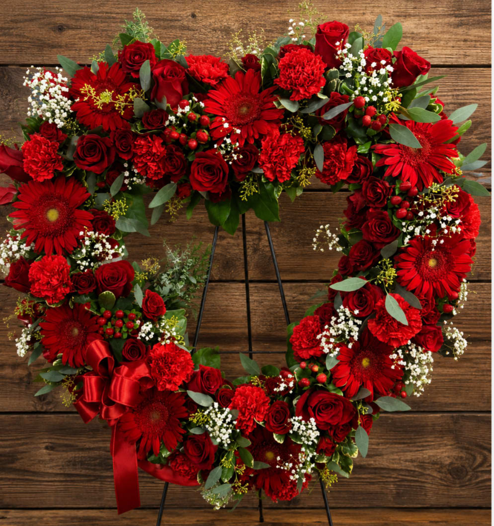 Heart-shaped red floral wreath on an easel with a ribbon bow