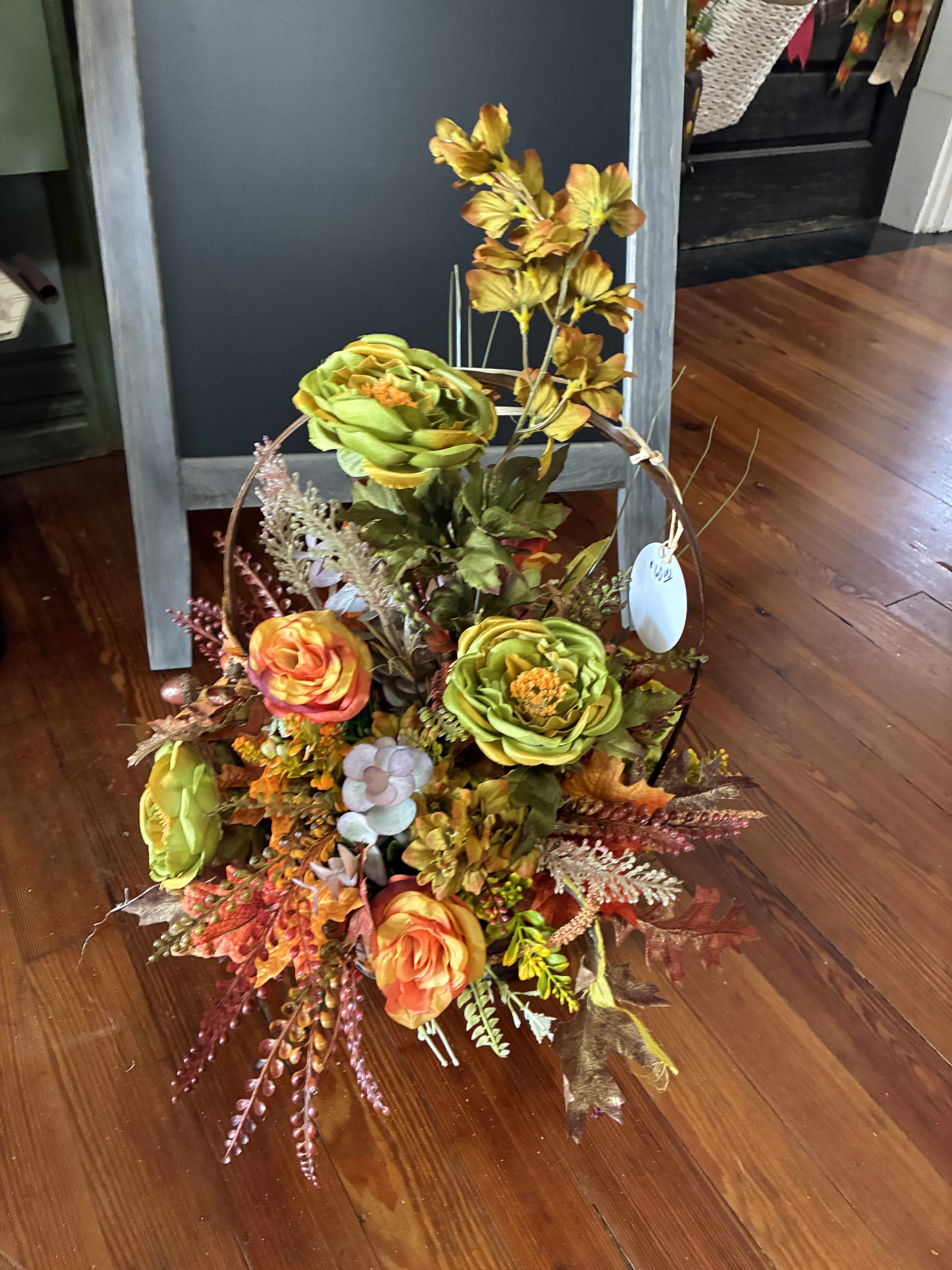 Autumn floral basket with orange and green blooms and fall foliage