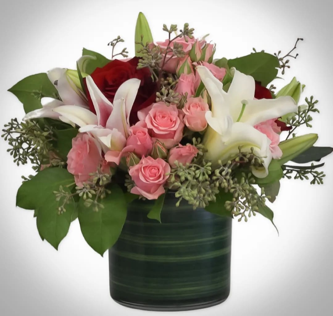 Pink and white roses with lilies in a dark green vase
