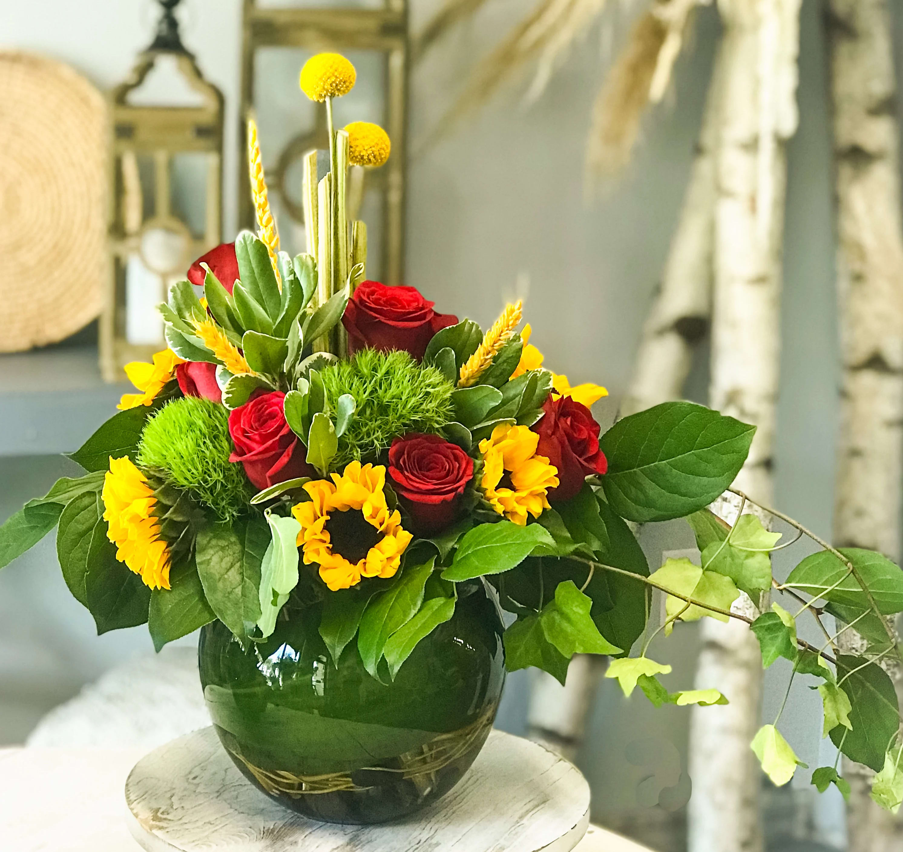 Red roses and yellow flowers arranged in a dark glass vase