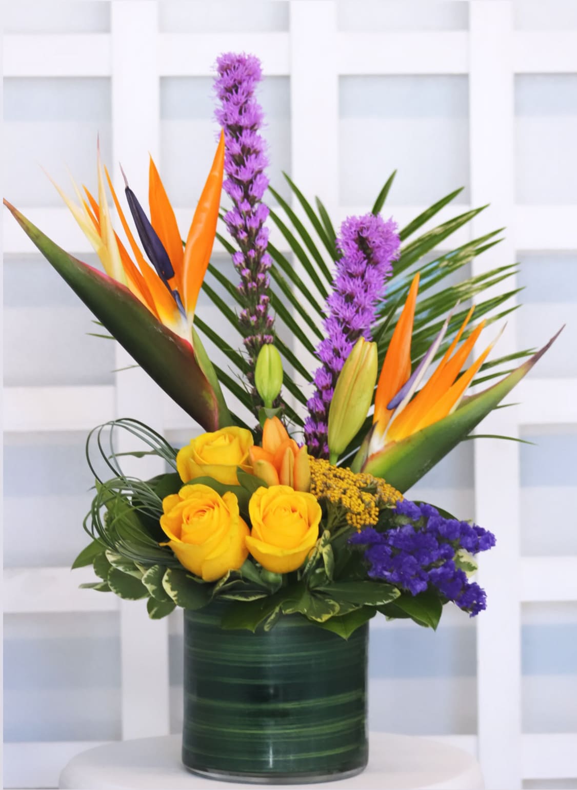 Tropical bouquet with yellow roses and bird of paradise in a green vase