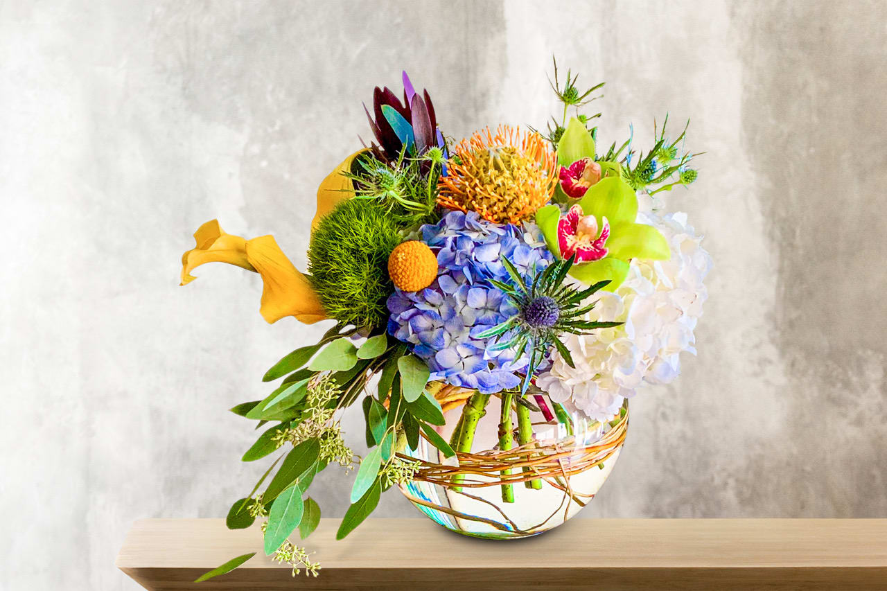 Colorful mixed bouquet in a round glass vase with a wicker wrap