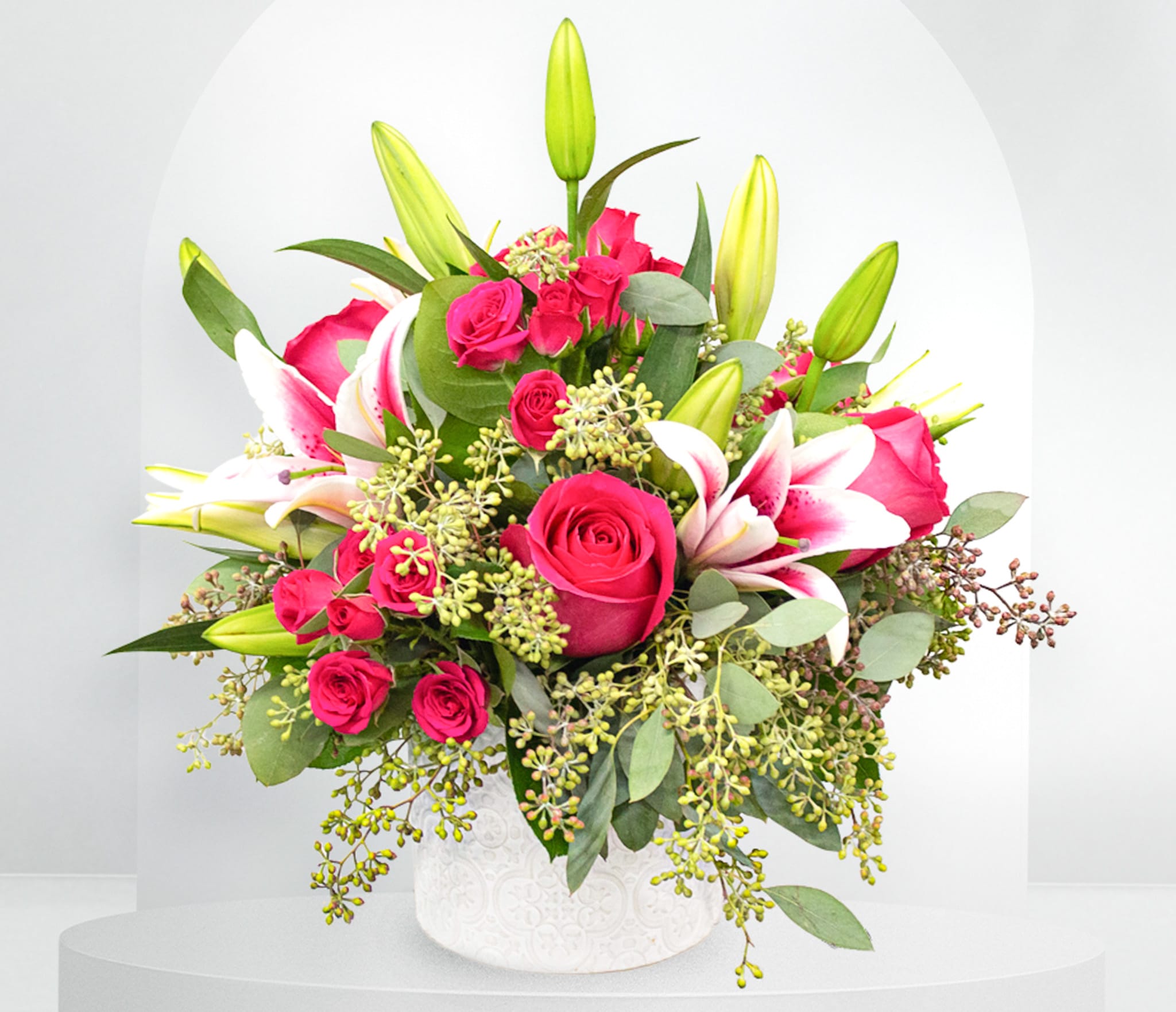 Pink roses and white lilies arranged in a white vase