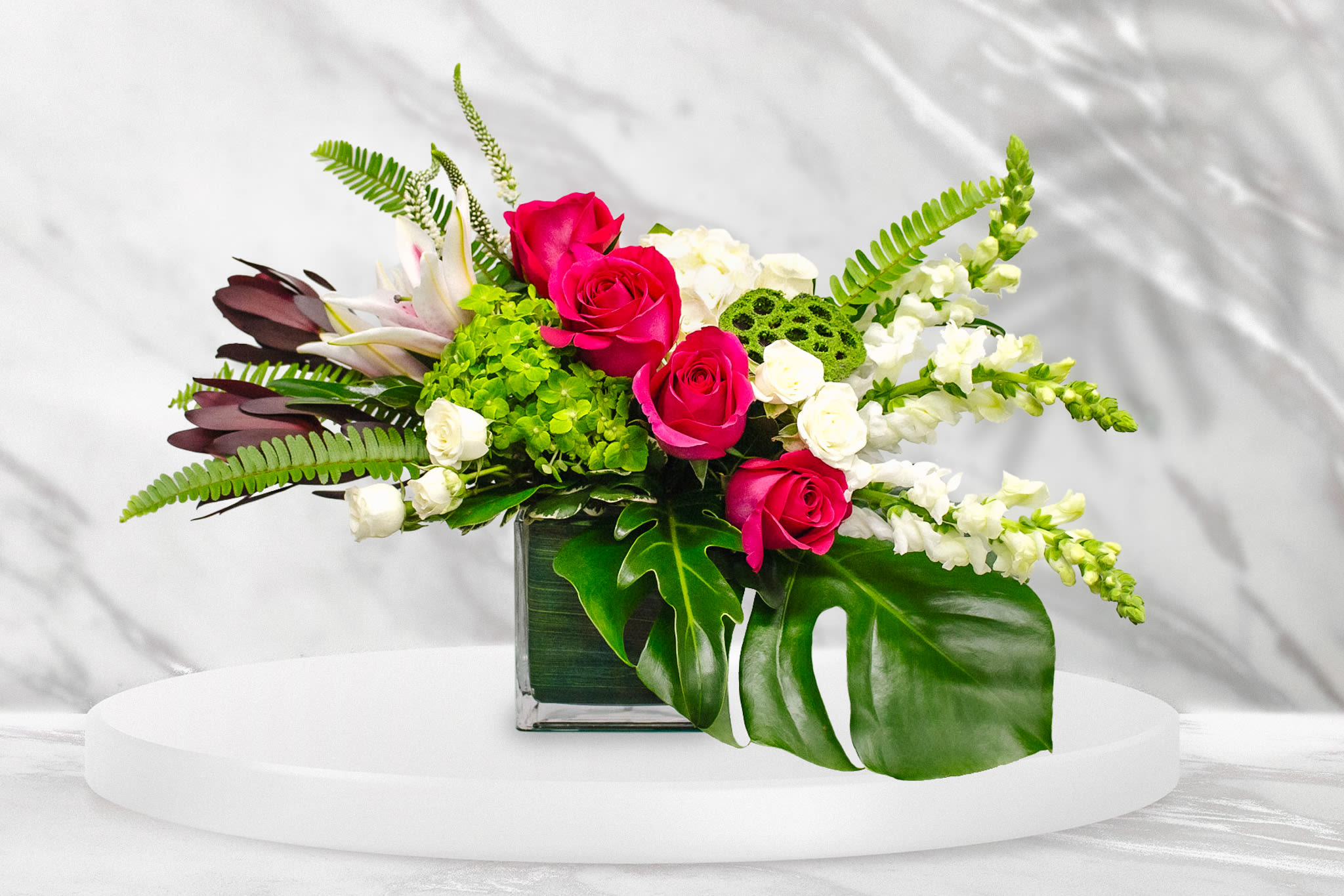 Pink roses and white flowers in a square glass vase