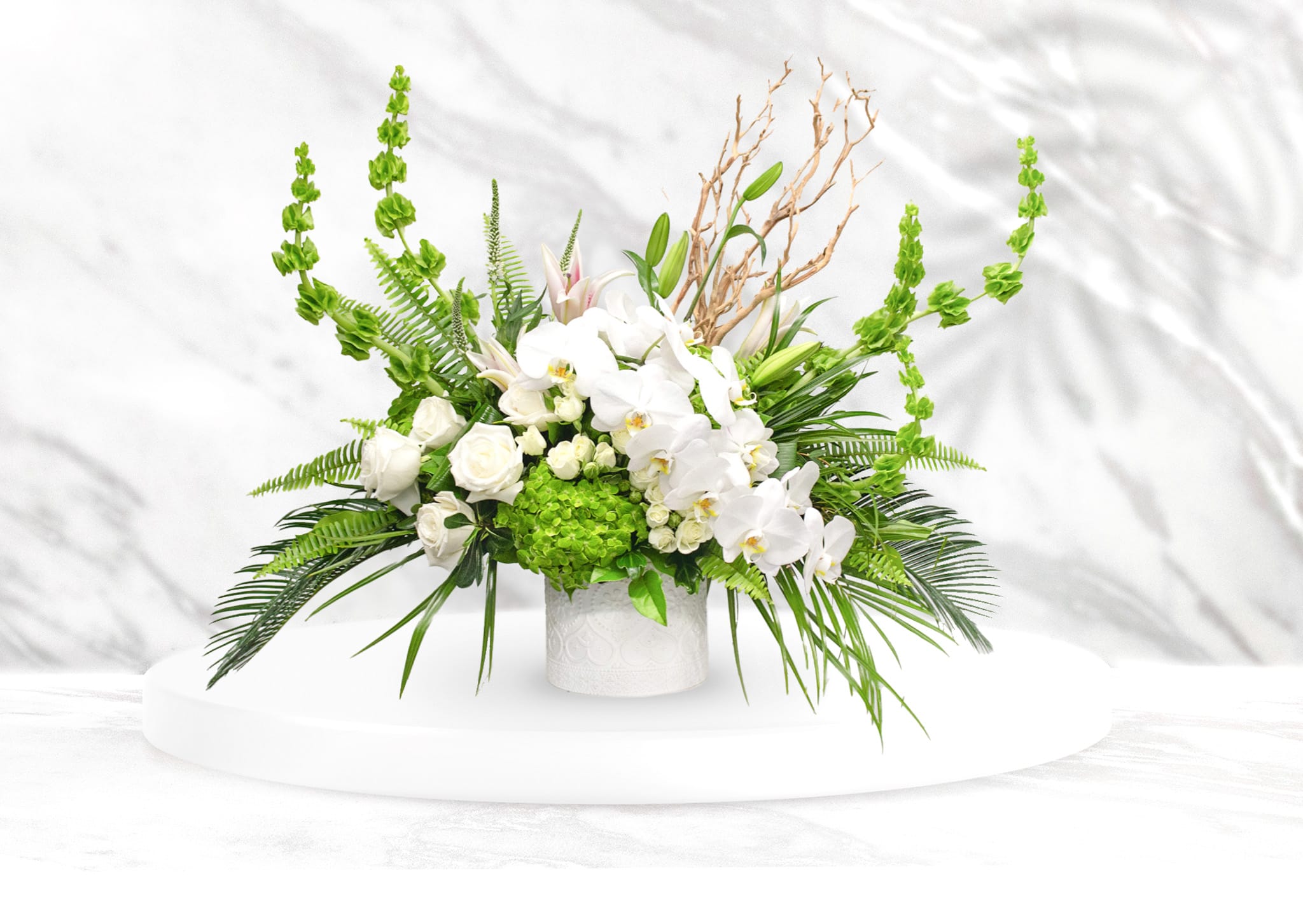 White orchids and roses in a white vase with bright green accents