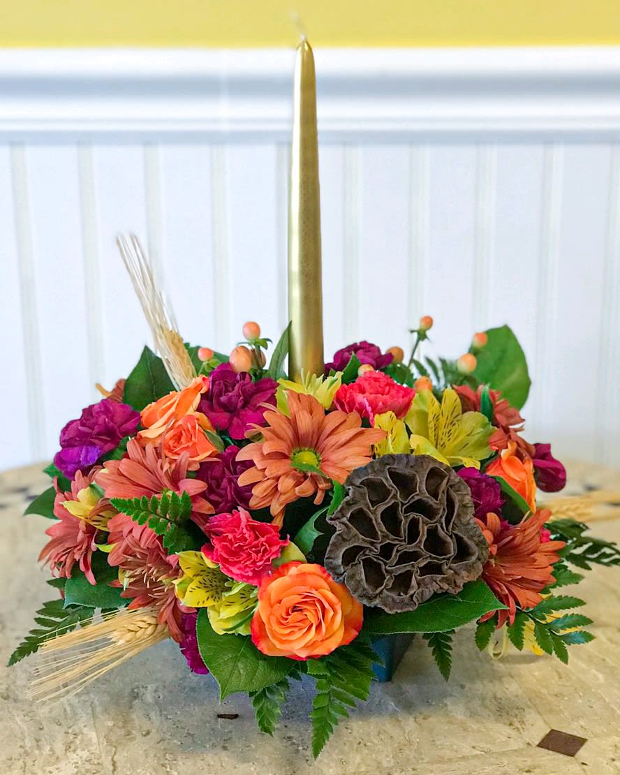 Colorful floral centerpiece with a tall gold taper candle
