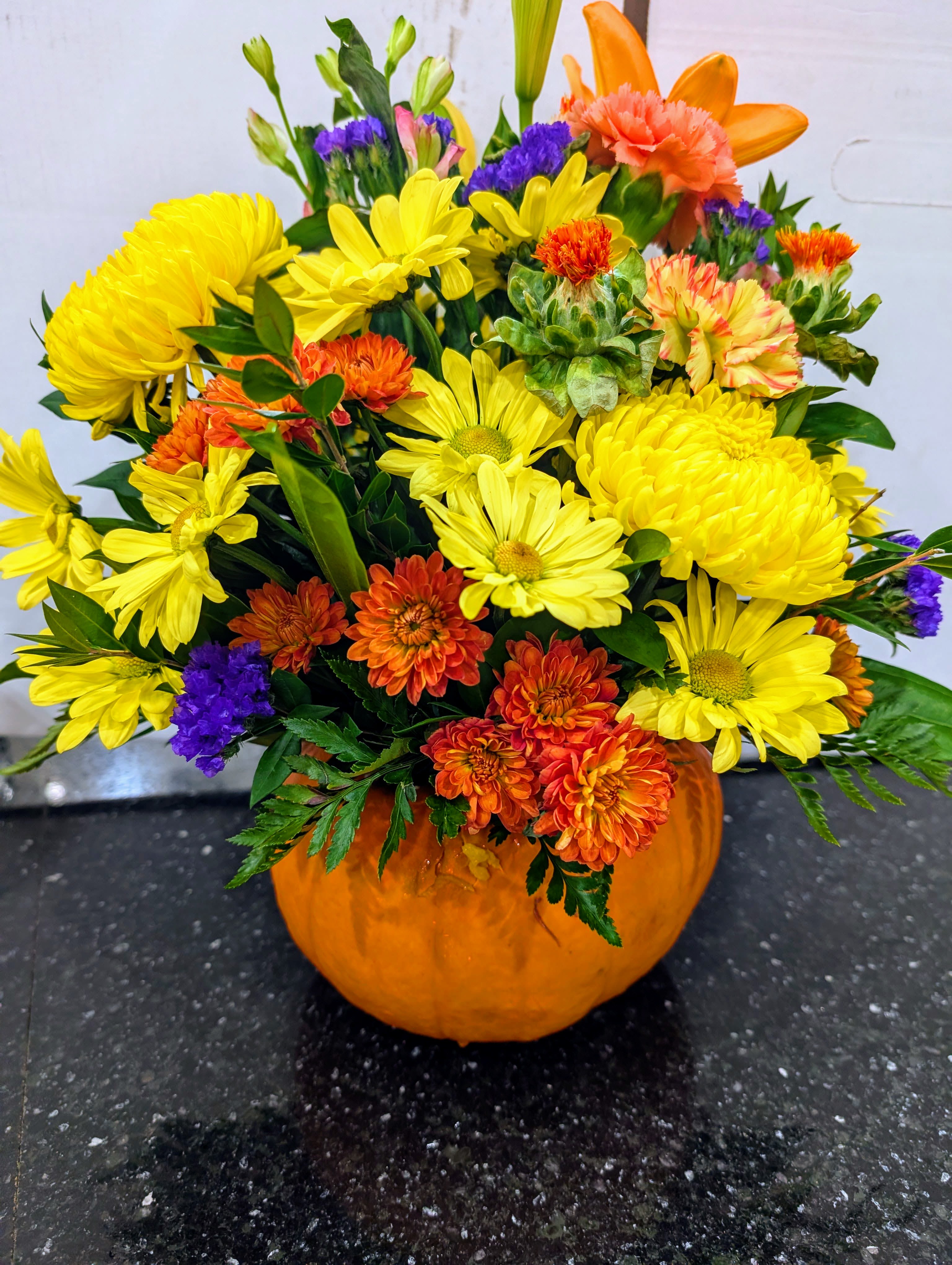 Mixed yellow and orange flowers arranged in a pumpkin container