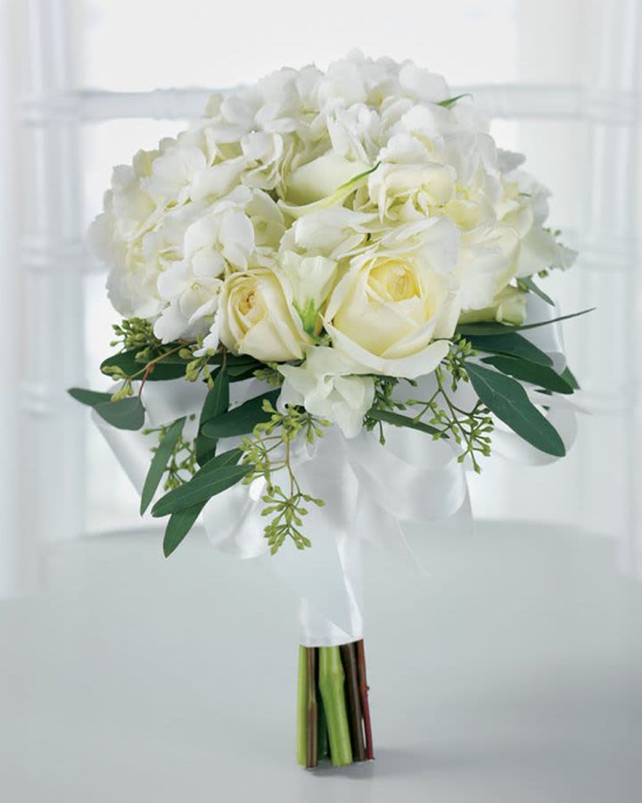 White rose and hydrangea bouquet with green foliage wrapped in white ribbon