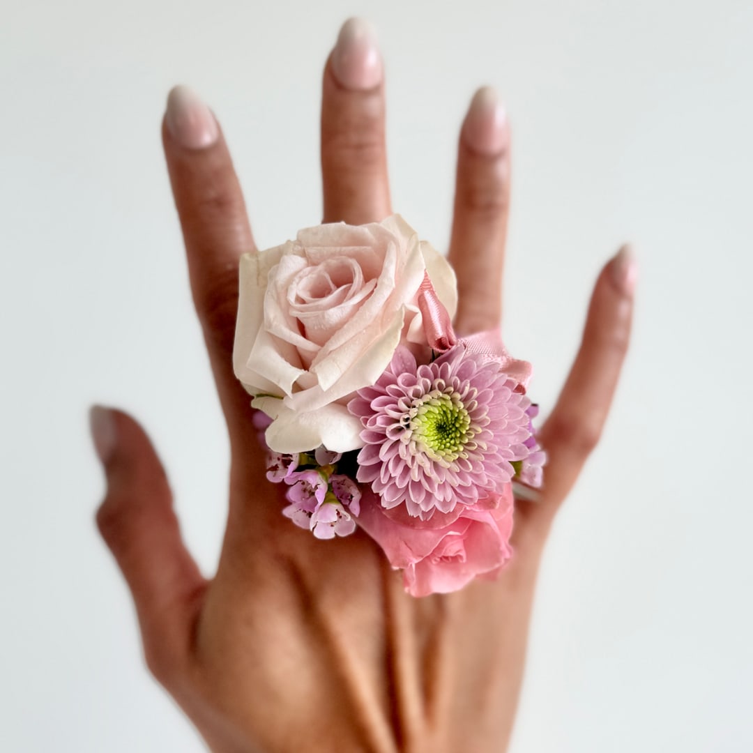 Pink floral ring on a hand with a pale rose and daisy-like blooms