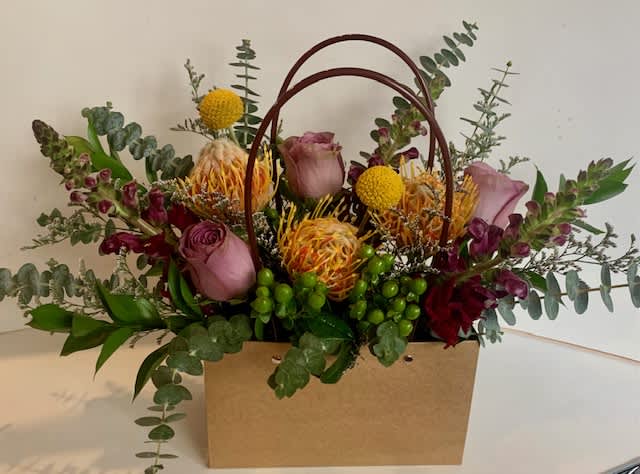 Portable and Pretty Pin Cushions - Handled craft paper bag houses this modern mix of pin cushion protea and burgundy snapdragons, Great for gifting!