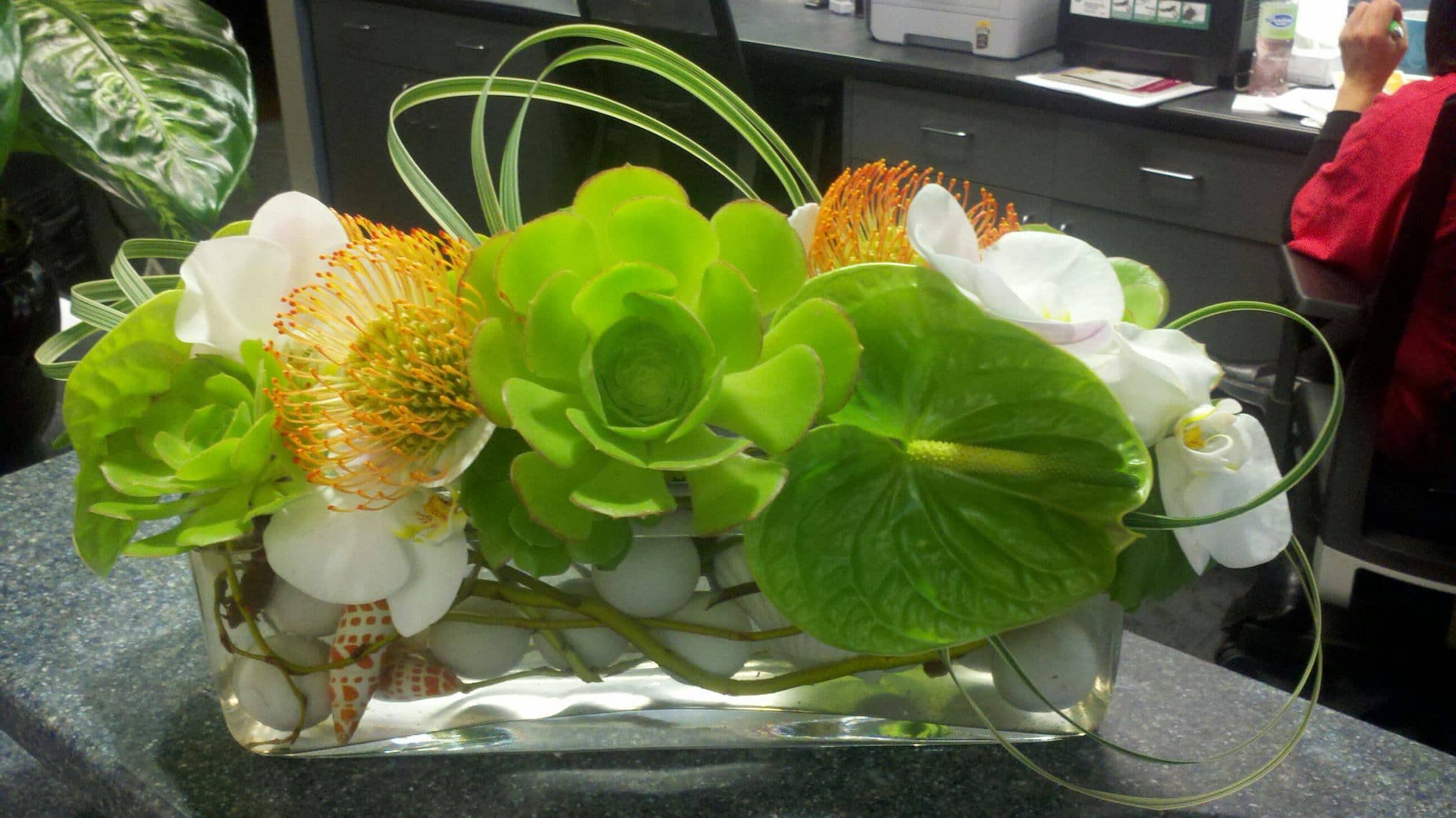 Green and white floral arrangement in a rectangular glass vase