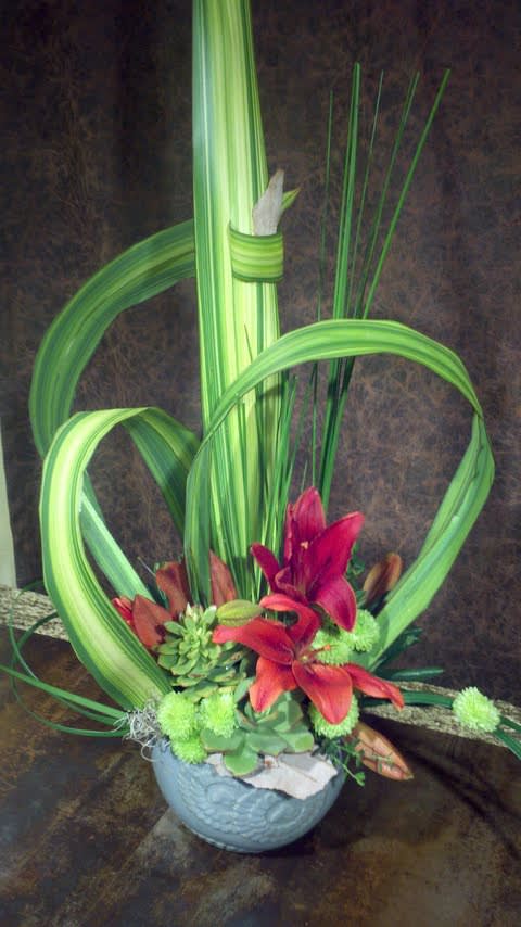 Tropical floral arrangement with red lilies in a blue bowl