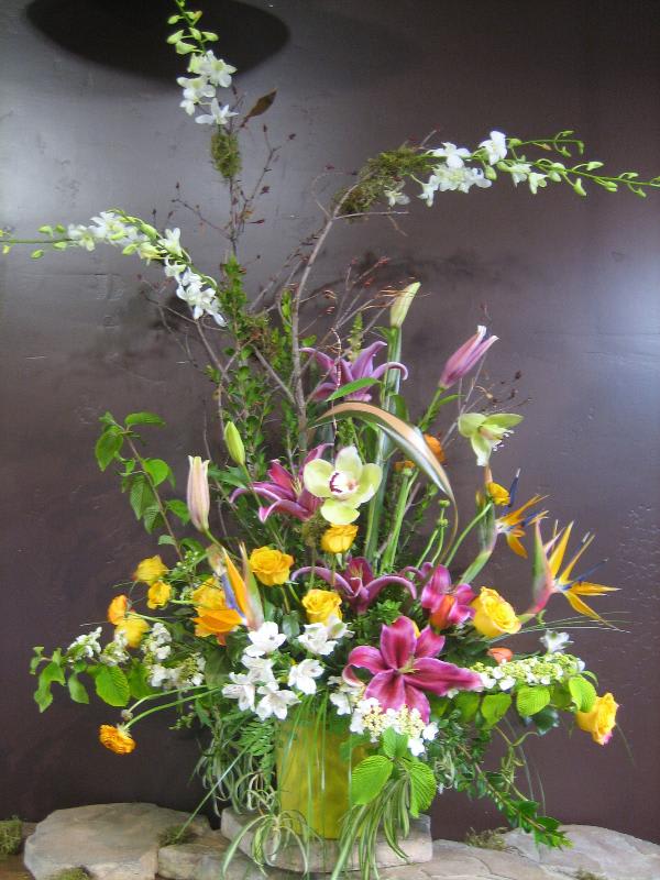 Tall mixed floral arrangement with lilies, roses, orchids, and bird of paradise