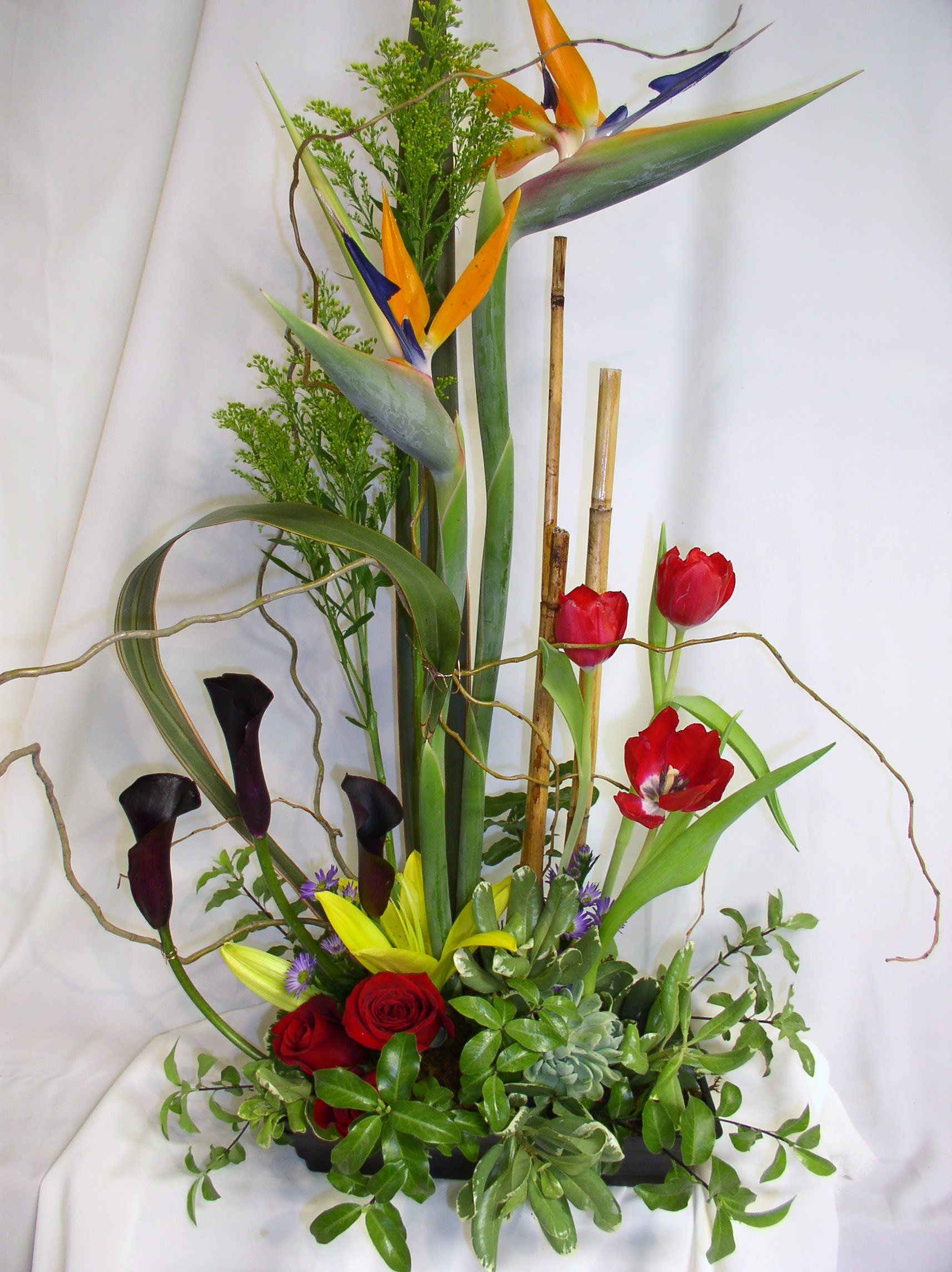 Tall tropical floral arrangement with birds of paradise, tulips, roses, and calla lilies