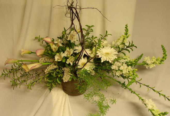 White floral arrangement with calla lilies and daisies in a brown vase