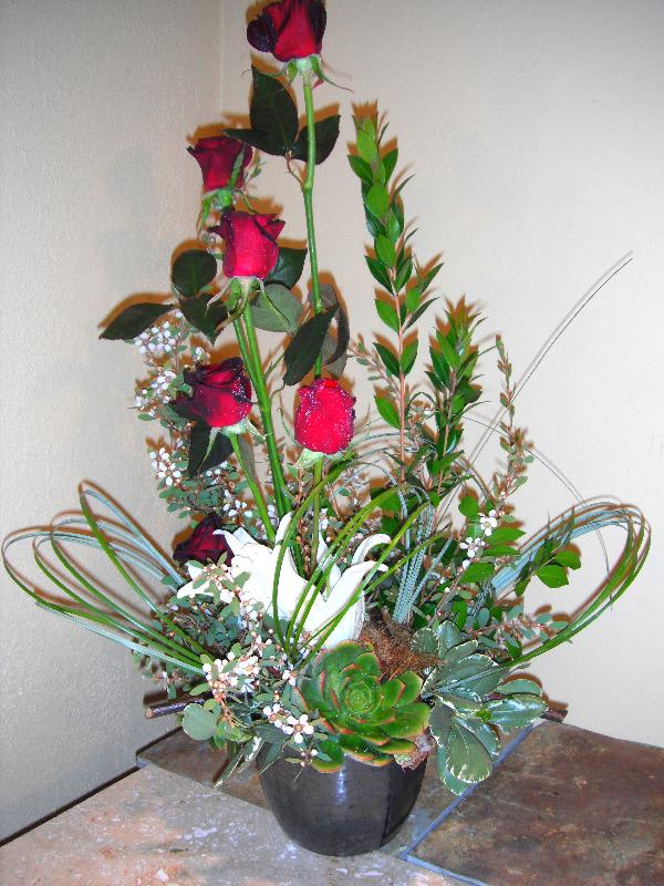 Tall arrangement of red roses and succulents in a black pot