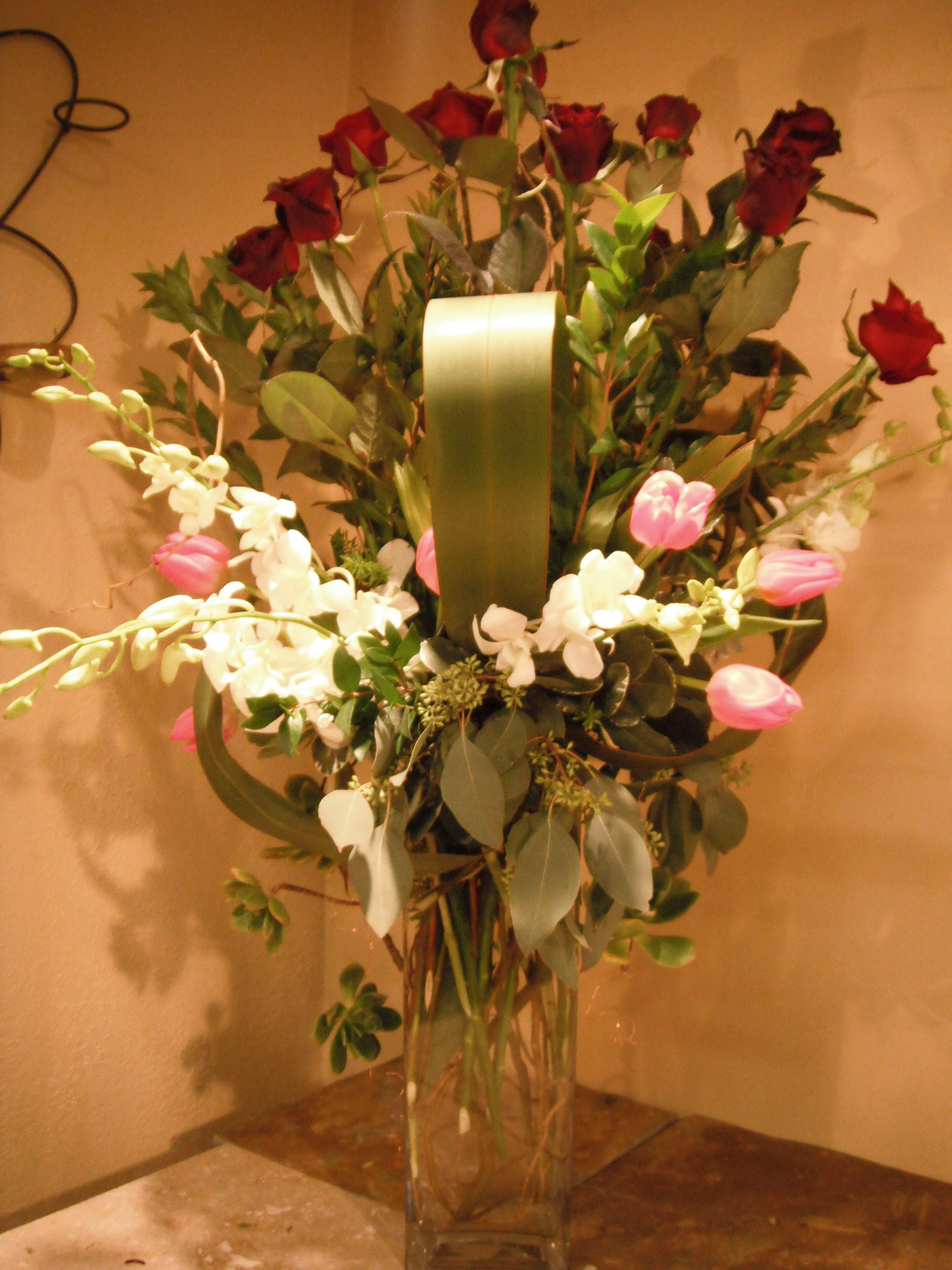Tall bouquet of red roses and white orchids in a clear glass vase