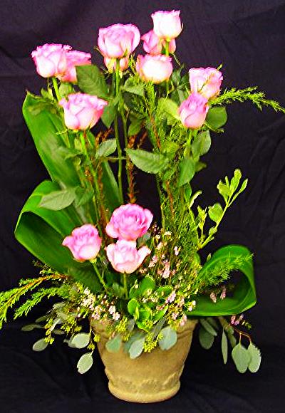 Pink roses arranged in a gold pot with greenery